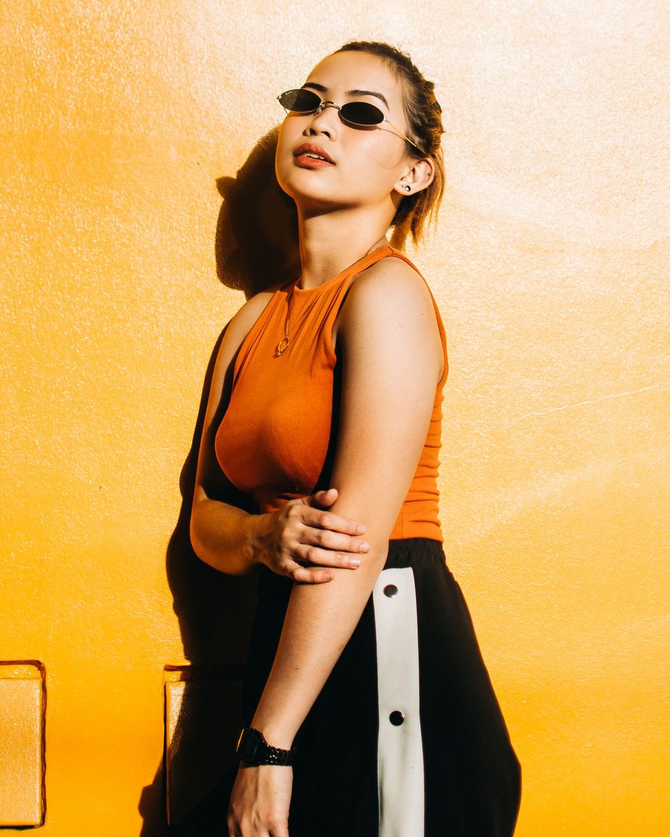 A woman in a narrow oval frame against a sunlit orange wall